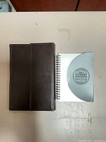 Tablet folio closed beside spiral notebook on surface