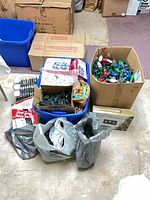 Bulk lot showing bins, bags, and boxes of assorted Christmas lights and stakes