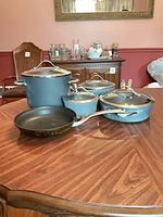 Entire cookware set displayed on table: one stock pot with lid, three saucepans with lids, one frying pan