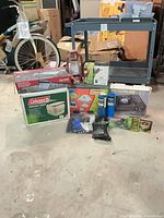 Group shot of all camping items including Coleman toilet box, lantern, stove box, grill box, fuel, tarp