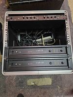 Rack case open showing two Carver PM 700 amplifiers and cables