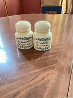 Front view of both shakers showing French labels and floral decoration