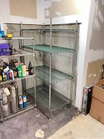 Full view of chrome wire shelving unit against wall, four shelves installed
