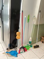 Group shot of all cleaning tools leaning against fridge and wall
