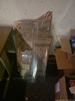 stacked clear glass panels leaning against wall, paper wrapping visible