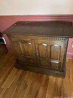 Front view of closed cabinet showing overall design, color, paneled doors, dentil trim