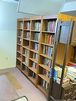 Angled view of all four connected brown bookcase sections filled with books