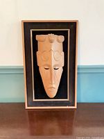 Front view of framed wood mask wall art
