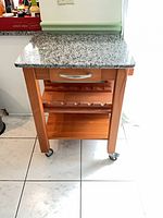 Full view of kitchen cart showing granite top, drawer, wine rack, shelf, casters