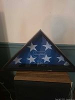 Front view of triangular flag display case with folded flag inside