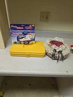 Handy Stitch box, yellow storage case, fabric pincushion basket on countertop