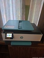 Front three-quarter view showing HP OfficeJet Pro 8028e printer body, teal lid, control panel, and overall condition