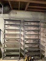 Two gray steel shelving units side by side against wall