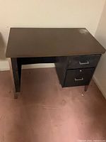 Front view of desk showing brown top, black frame and drawers