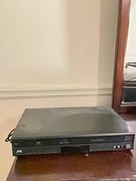 Front angle of JVC black DVD/VCR combo showing brand logo, DVD tray and VHS slot