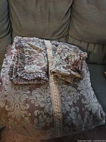 Folded comforter with fringed pillow and shams on sofa