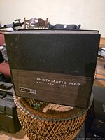 Closed projector showing Instamatic M67 branding and faux wood panel