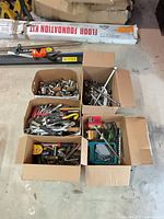 Six open boxes filled with assorted hand tools on workshop floor