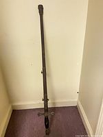 Sword with scabbard standing upright against wall
