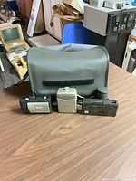 Overall lot showing three cameras in front of gray carry case