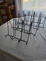 Group view of eleven black metal easel stands on table