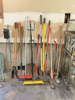 All 15 long-handle garden tools leaning against wall
