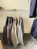 Upper rack with dark, cream and grey blazers on hangers