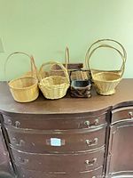 Six baskets on dresser showing variety of shapes, natural and dark colors
