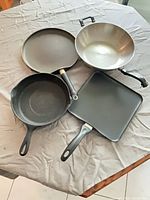 Group view: cast iron skillet, square nonstick griddle, round crepe pan, stainless steel wok