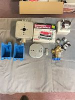 Group shot of all items laid out: two blue plastic boxes, two metal boxes, boxed Arista switch, brass valve, contactor, small fittings