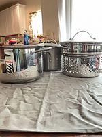 Stock pot, steamer insert with lid, additional pot visible