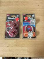 Blister packs showing two red dial padlocks and one orange 4-wheel lock