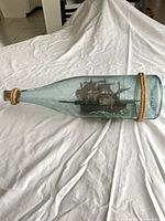 Full view of glass bottle with rope trim and ship inside