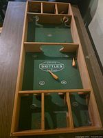Full view of wooden skittles board on table with pins visible