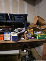 Assorted boxed parts on wooden shelf including Fram filter, Champion, GE, Daytona, plus air compressor below