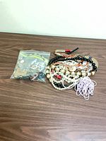 Bag of small jewelry pieces alongside tangled necklaces