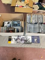 Two banker boxes filled with CDs; four notable box sets laid out in front