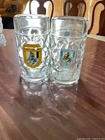 Front view of both glass steins showing crests