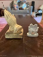 Both praying hand figurines side by side on table