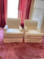Front view of both armchairs showing overall style, color and skirted slipcovers