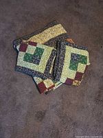 Folded quilt with two pillow shams stacked on carpet