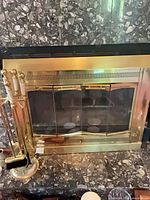 Front view of brass fireplace surround installed in marble hearth