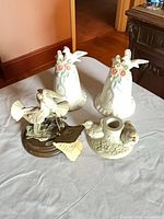 All four items: two porcelain bells, metal bird figurine on wood base, porcelain bird candle holder