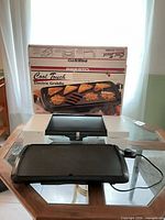 Presto griddle in front of original box, cord visible
