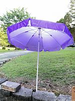 Opened purple beach umbrella standing on retaining wall