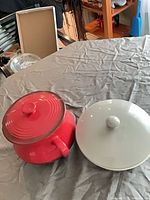 Red and gray covered casseroles side by side, lids on