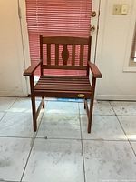 Front view of brown wooden slatted armchair