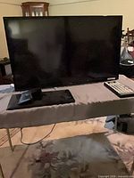 Full view of Seiki TV on stand with remote beside it