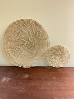 Large and small wicker rattan wall decor pieces leaning against wall
