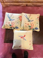 All three bird and floral pillows on surface